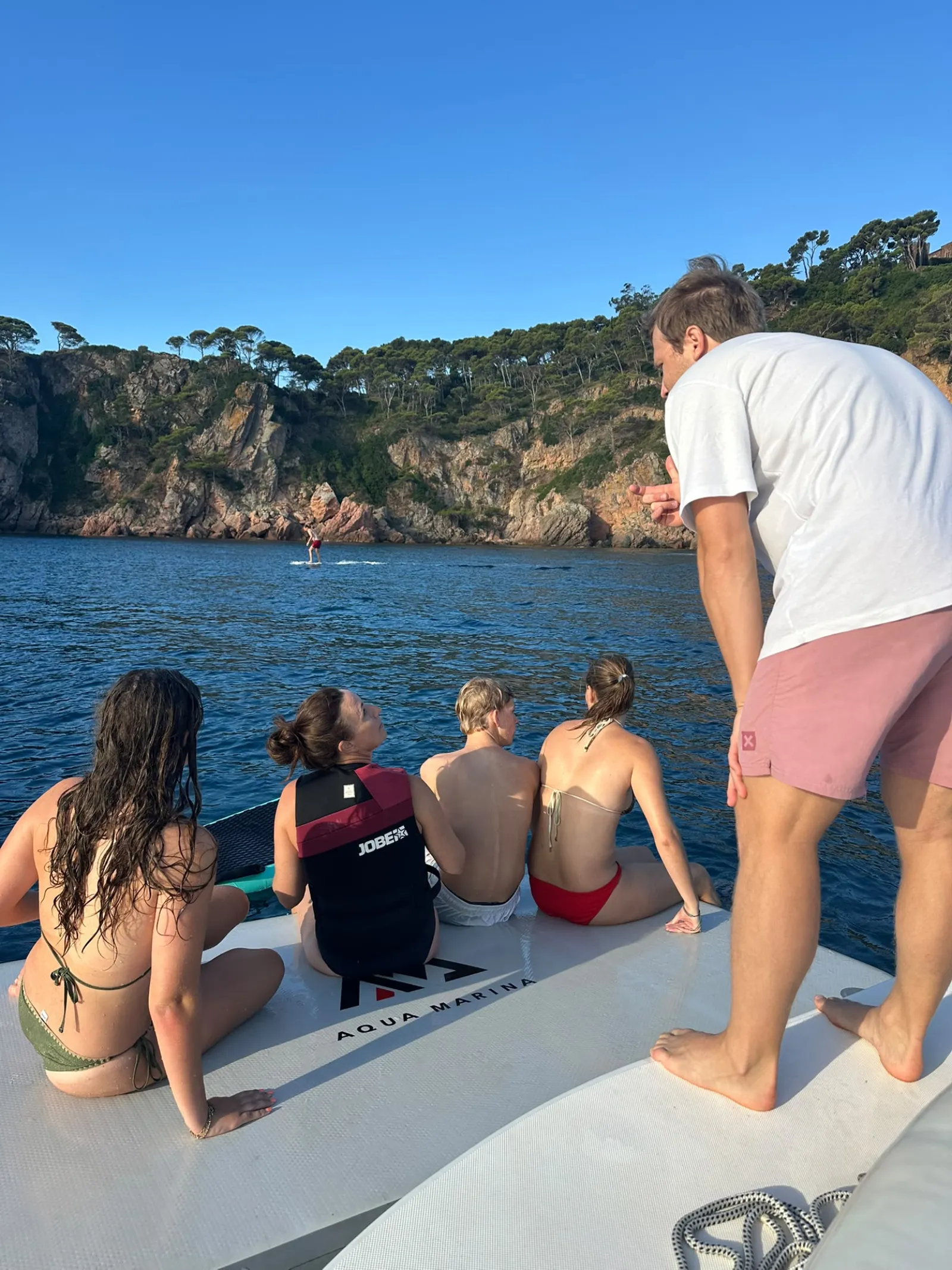 Instructor de e-foil con el grupo en la plataforma del barco en una cala de Llafranc